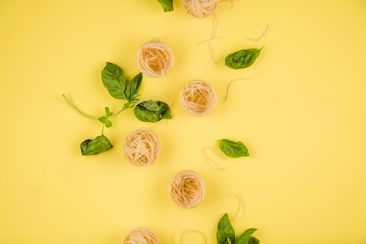 primer plano de pasta y albahaca. vista superior sobre el fondo amarillo. foto