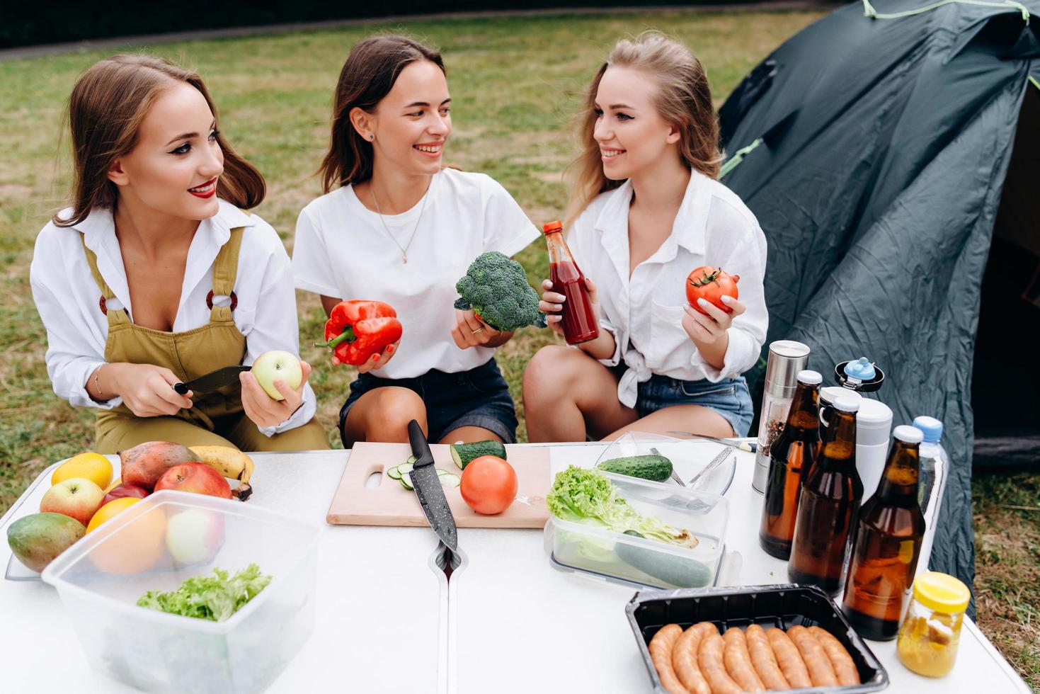 Young women sitting at the table and cooking smiling and looking each other photo