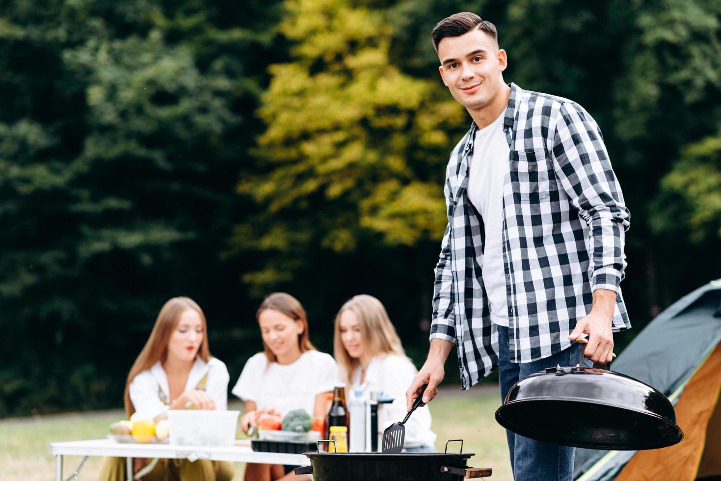 Chico joven de pie con la tapa de la barbacoa en la mano y mirando a la cámara foto