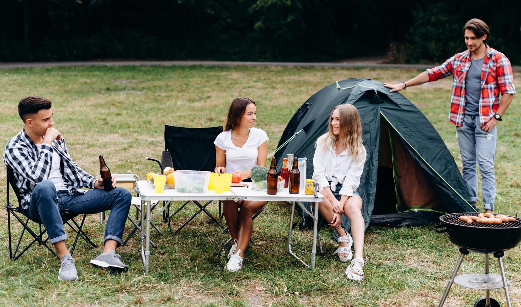 Young guys in the camping next a tent have a lunch and have a funny time photo