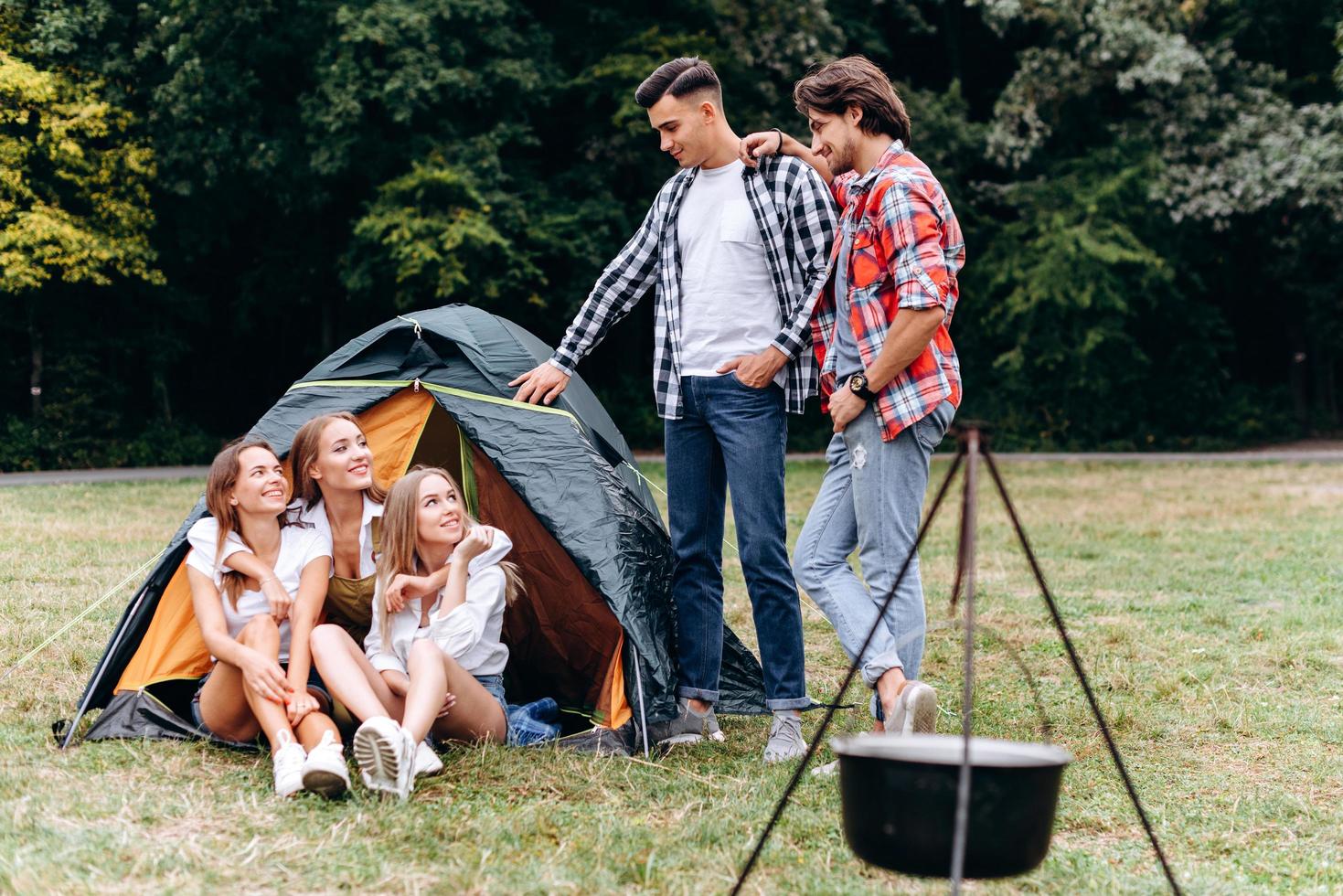 A company of friends next the tent. - Camping concept photo