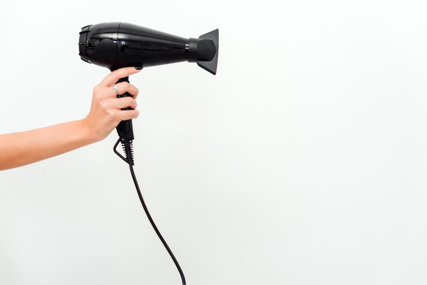 Mão feminina segurando secador de cabelo profissional isolado no