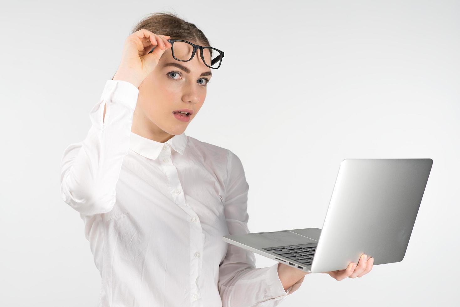 Amased business woman in glasses  holding laptop and raises up her glasses photo