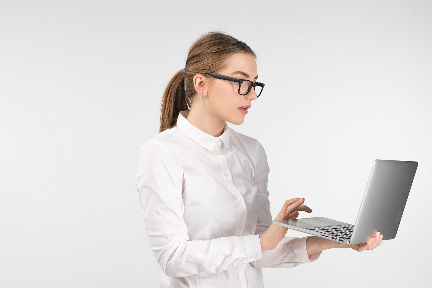 Woman in glasses  works on a laptop while standing. Looking carefully at the screen photo