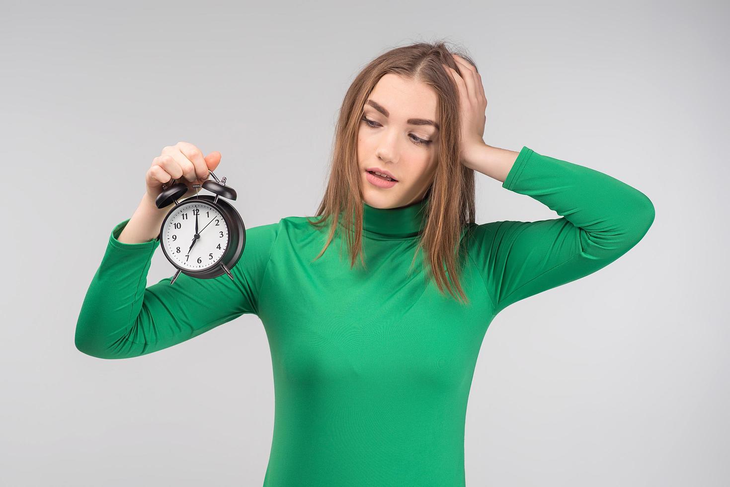 Young woman wearing casual clothes standing isolated over  background holding alarm clock - Image photo