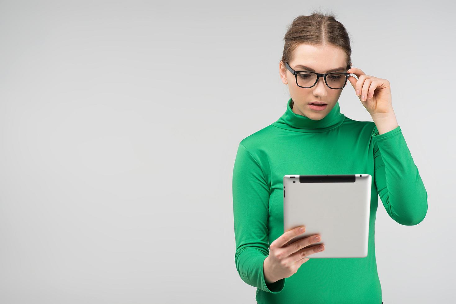 Girl surprised in profile looks on a tablet standing. - Front view photo