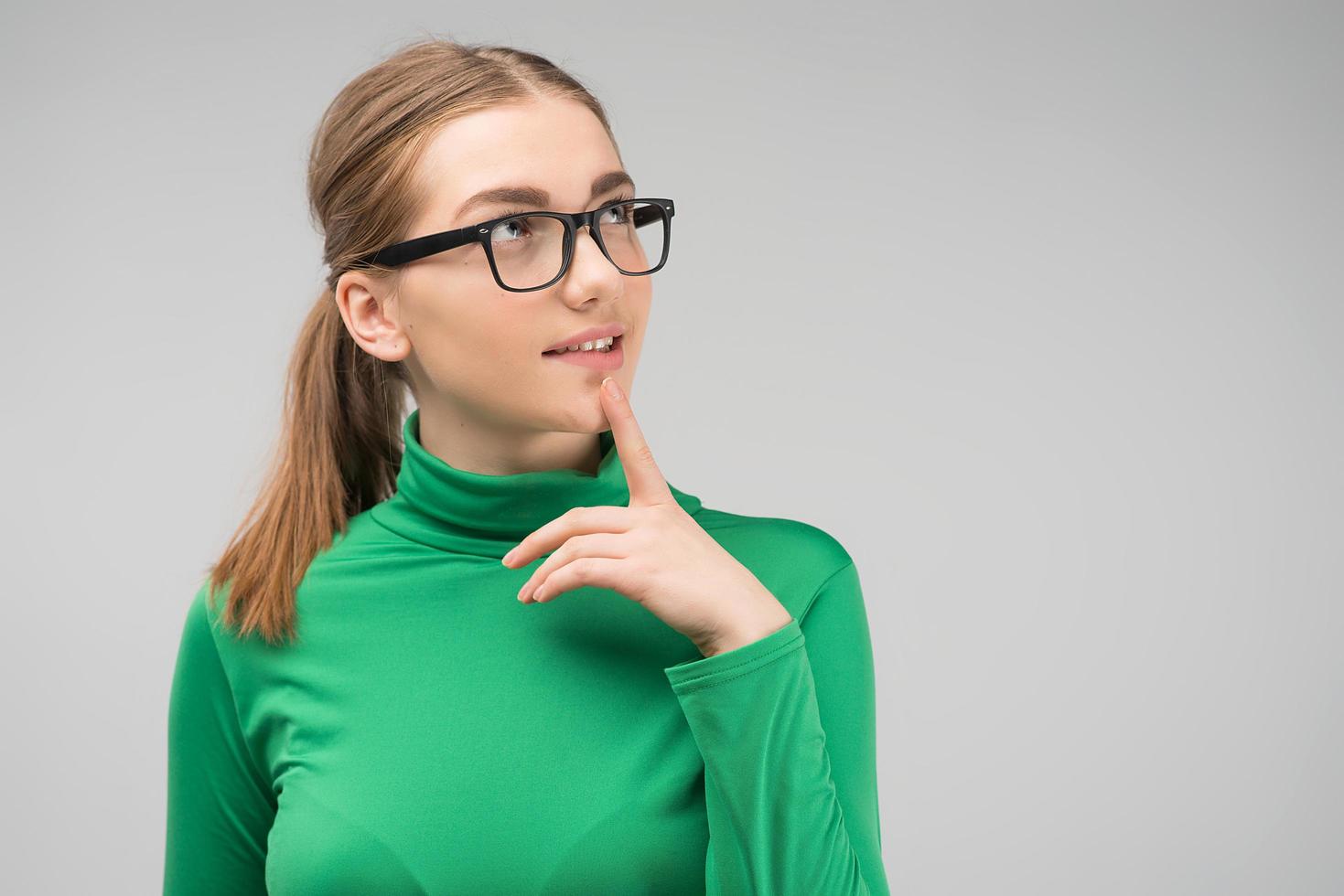 Young girl in glasses standing is thoughtful in the studio and looking up. - Image photo