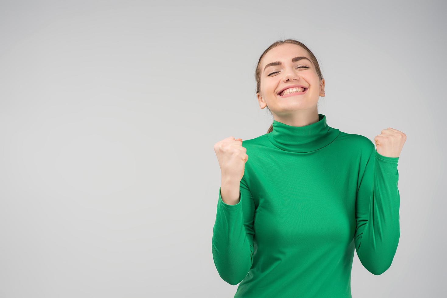 mujer joven con los ojos cerrados es feliz de pie en el estudio. emociones de alegría. lugar para el texto foto