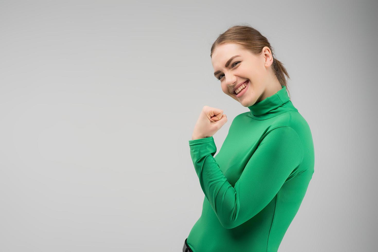 Mujer joven feliz mirando a la cámara con cleanch puño hacia arriba y sonriendo.- imagen foto