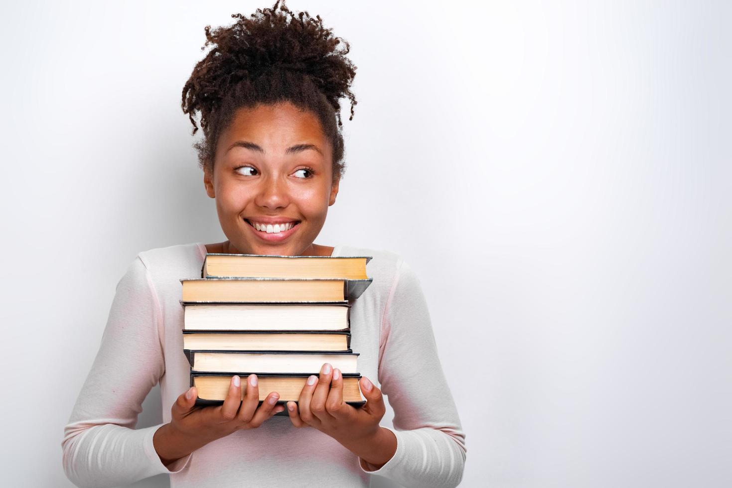 Portrait of happy nerd young girl holding books over white background. Back to school photo