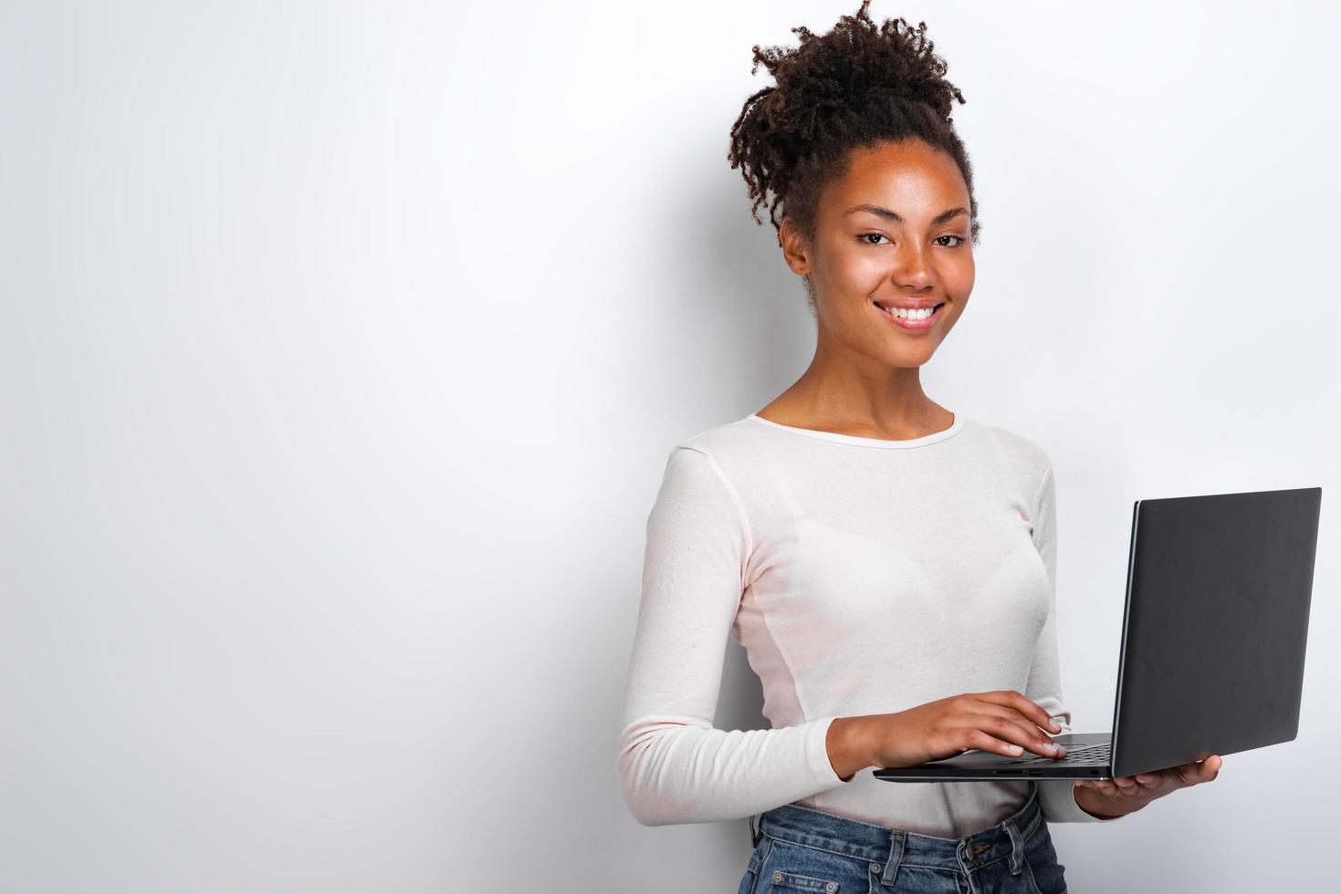 Portrait of happy young woman holding laptop computer over white background photo