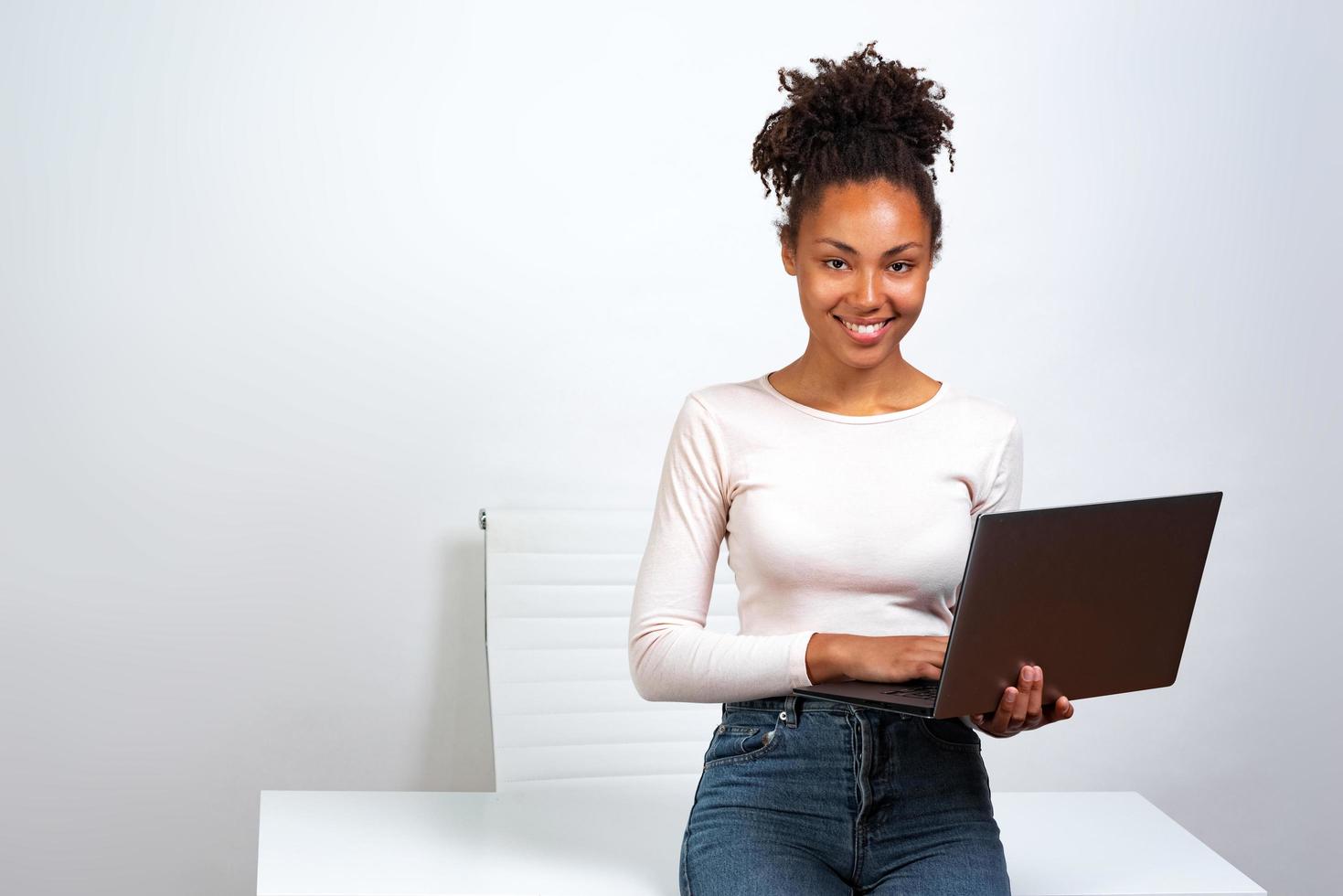 chica alegre descansar de pie en la oficina sosteniendo una computadora portátil foto