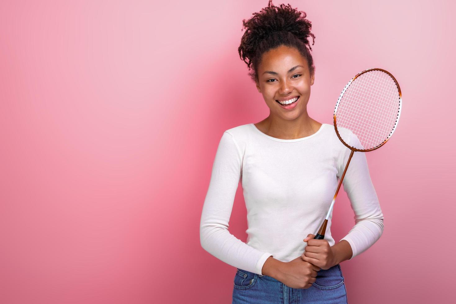 Chica deportiva de pie con raqueta de bádminton en el estudio mirando a la cámara foto