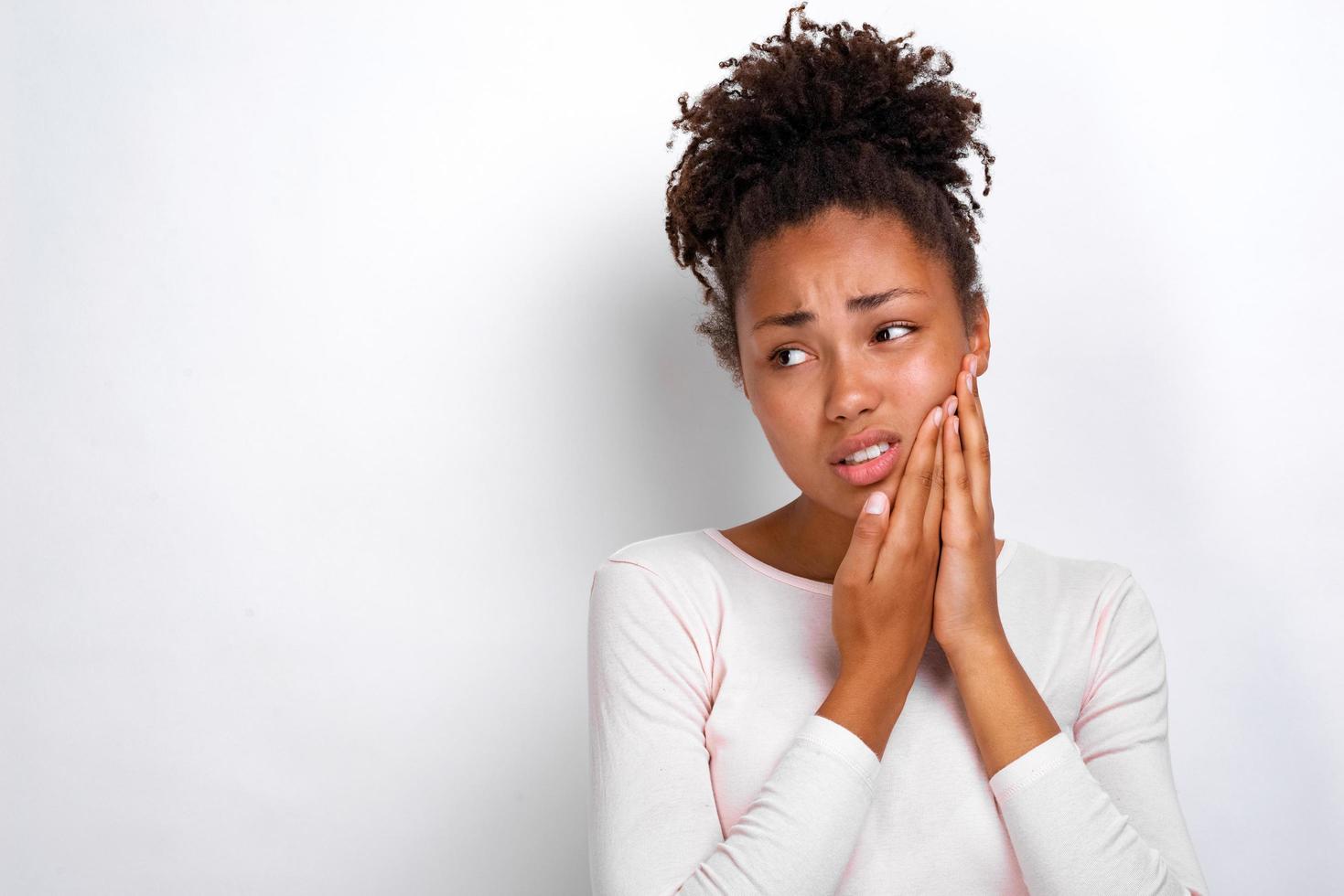 Studio portrait of sick woman touches herself cheek and looks unhappy photo