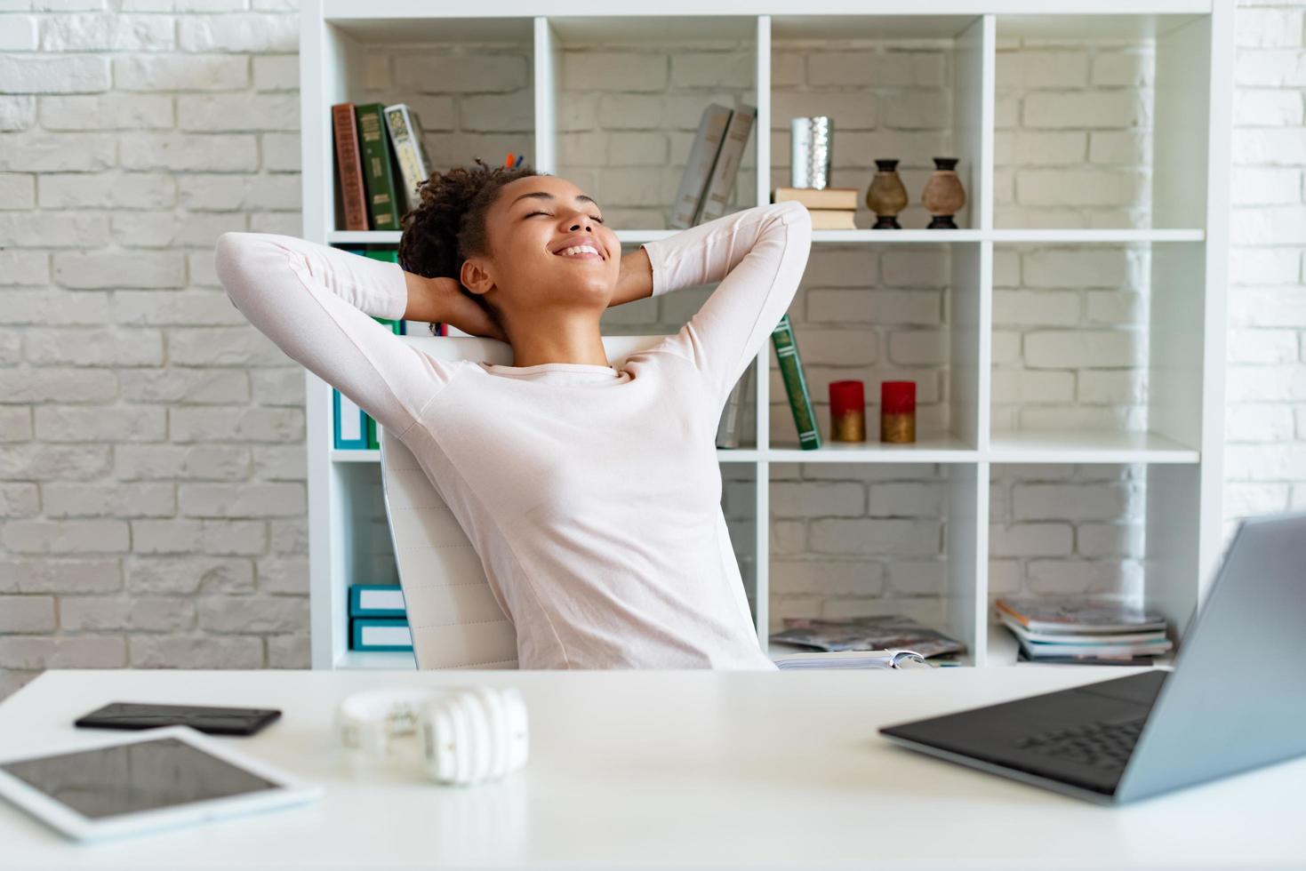 Happy woman have a break in office, folded arms by the head and lying the chair looking up photo