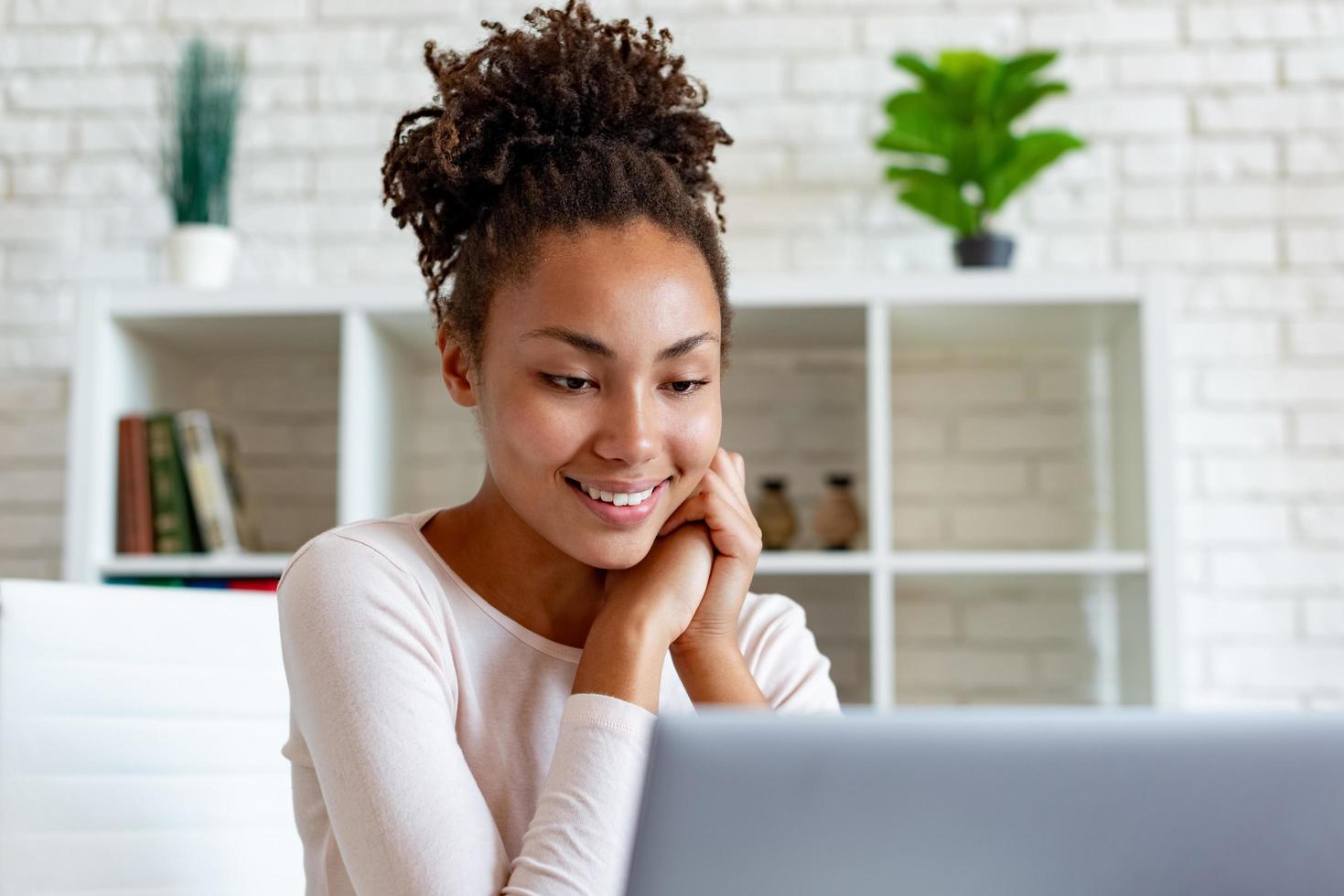 linda mujer mirando la pantalla del portátil sentado en la oficina y sonriendo suavemente. - imagen foto