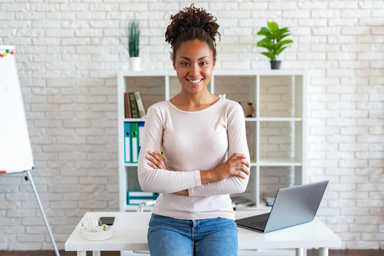 Happy woman have a rest in office, folded arms and smiling looking at the camera leaned the table photo