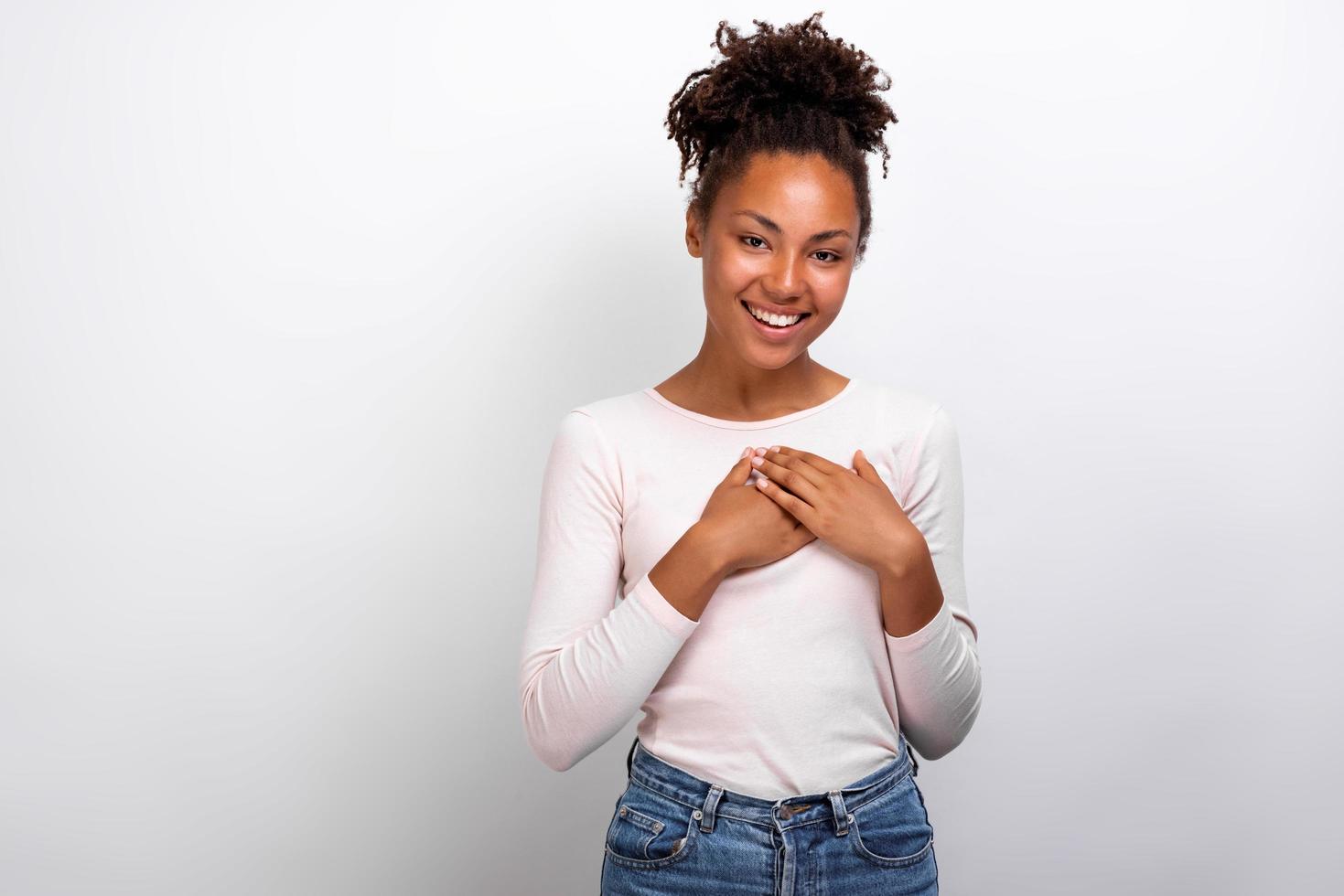 bonita mujer mulata muestra un gesto de amor gentilmente con los brazos sobre el pecho. gesto de concepto - imagen foto