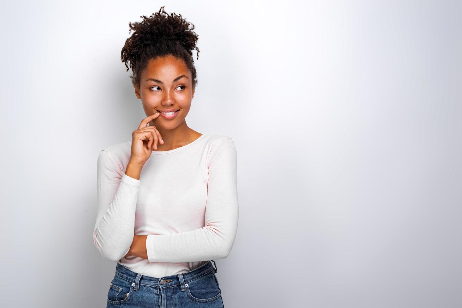 Retrato de estudio de una pose juguetona chica mulata tocándose la cara con el dedo índice- imagen foto