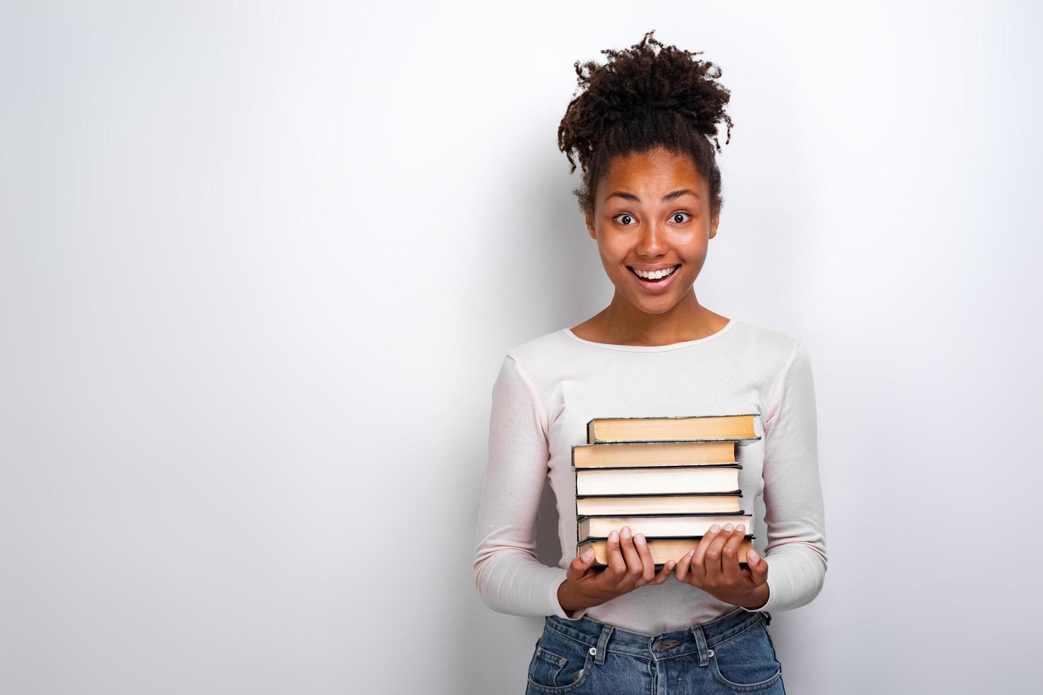 Retrato de una niña emocionada sosteniendo libros sobre fondo blanco. De vuelta a la escuela foto