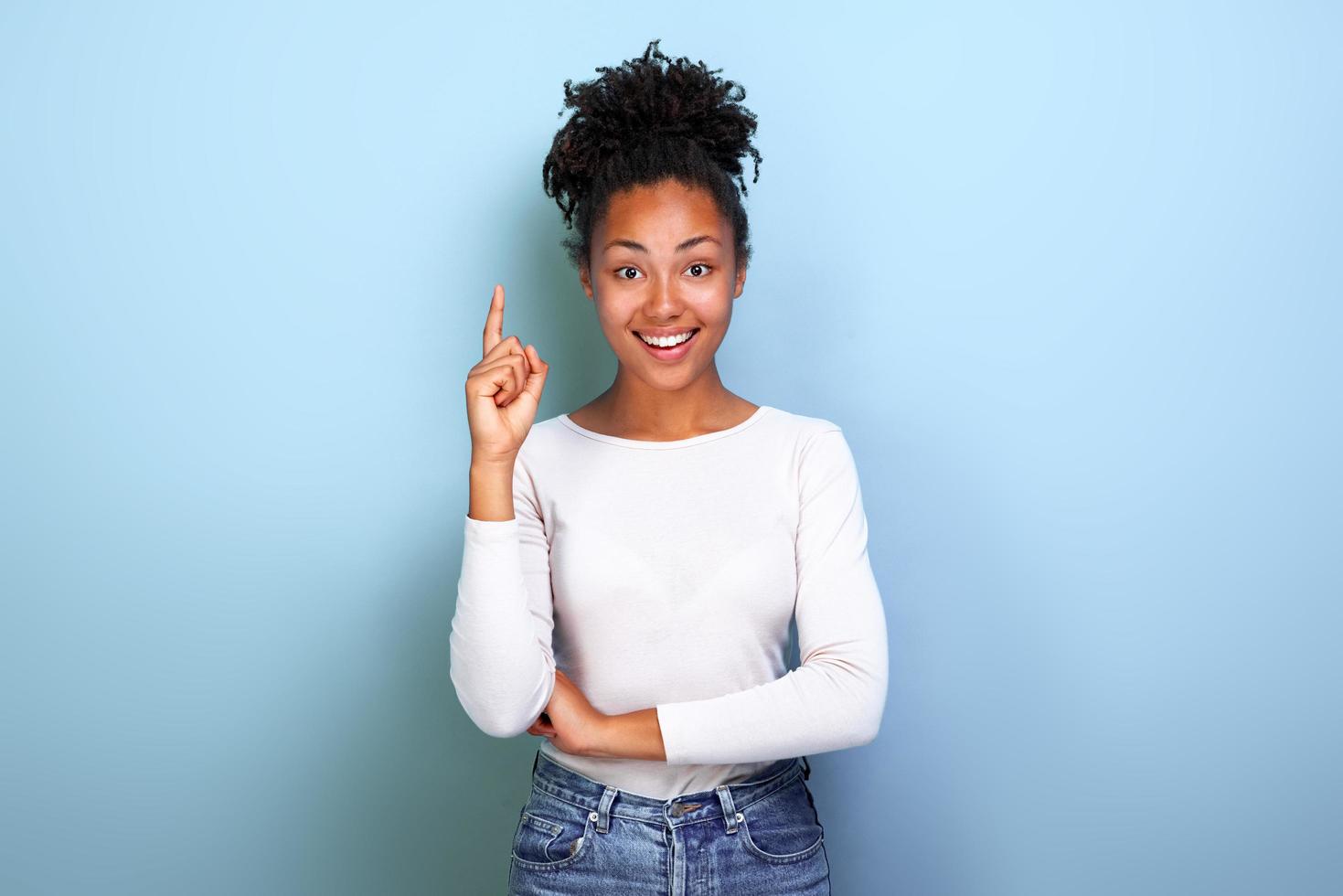 Atractiva mujer mulata feliz apuntando con su dedo índice hacia arriba foto