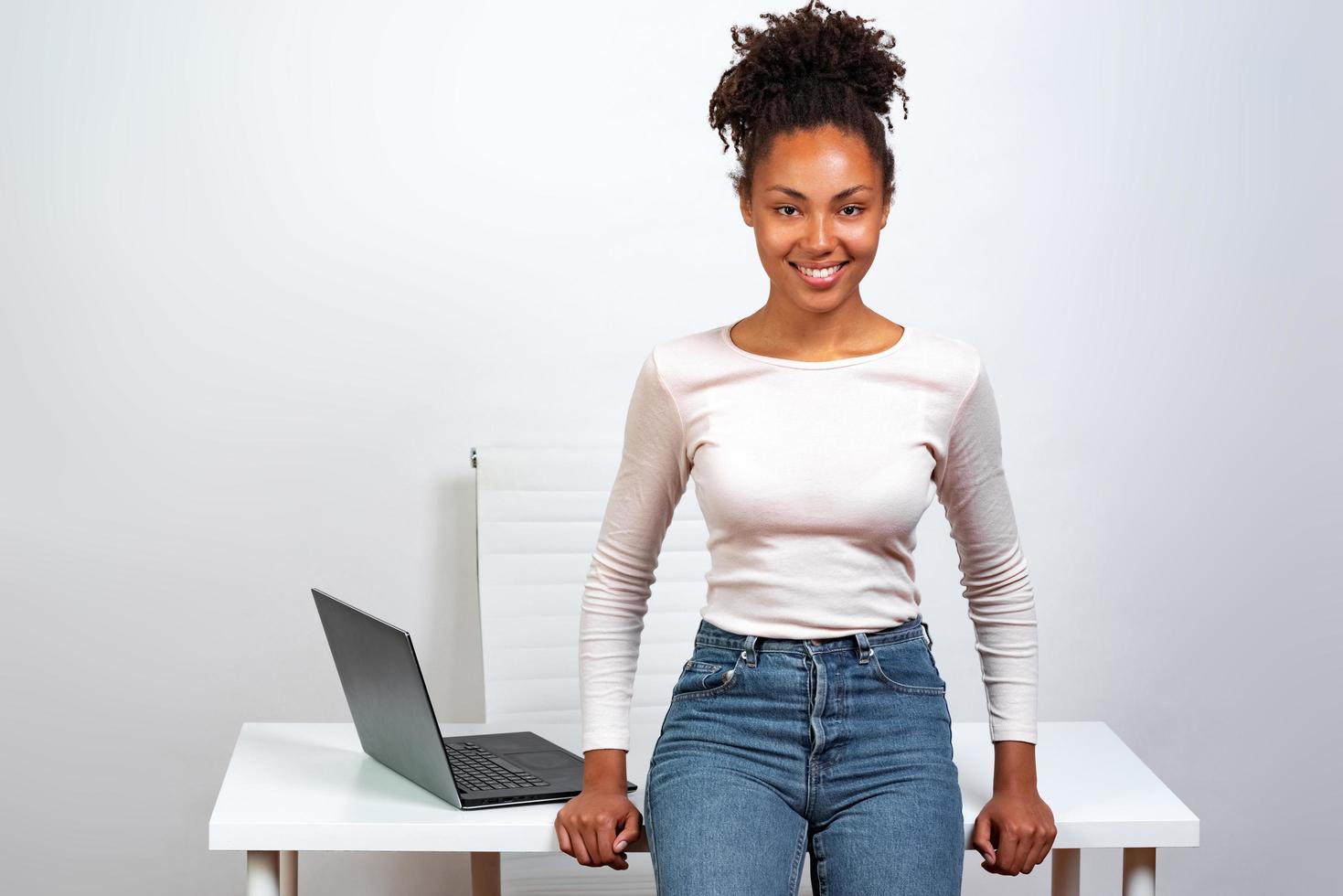 Happy woman in the office leaned to desk and looking at the camera photo