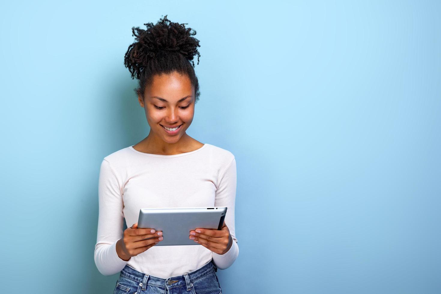 Smiling woman standing with ipad looking at the screen and happily smile photo