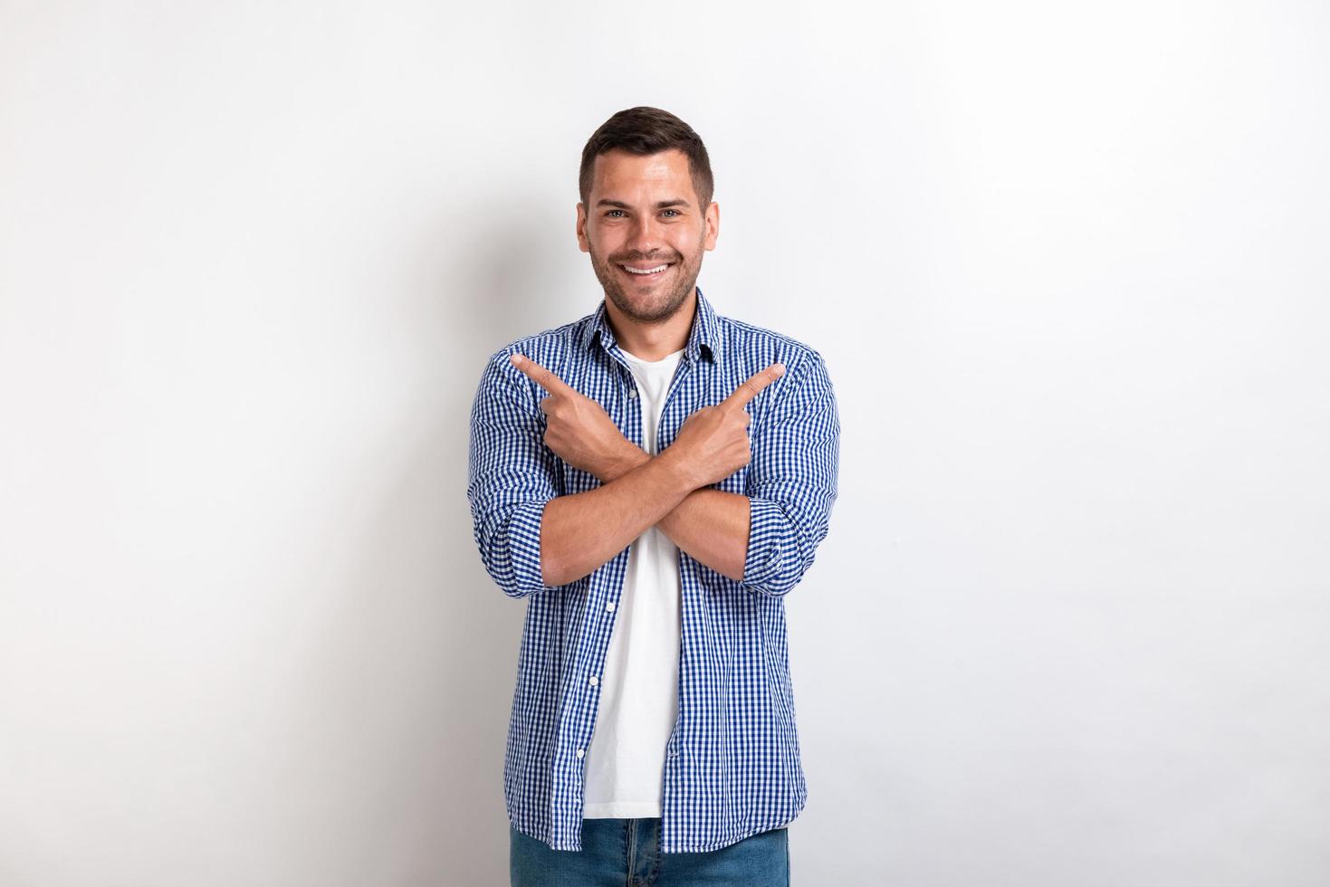 Man pointing his index finger in both side crossing his hands in the studio . - Image photo