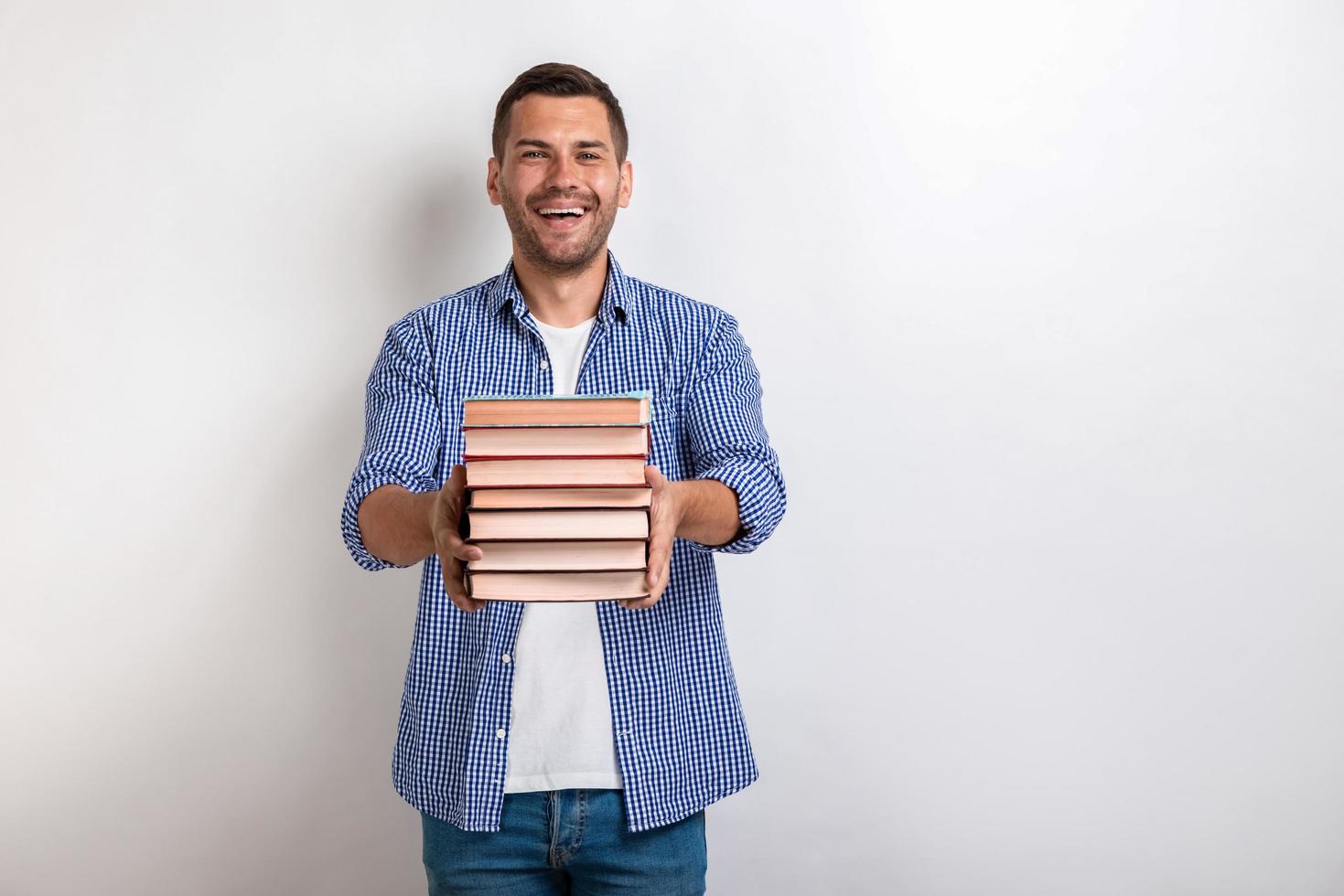 Portrait of happy young man holding books in his straight hands. Back to school photo