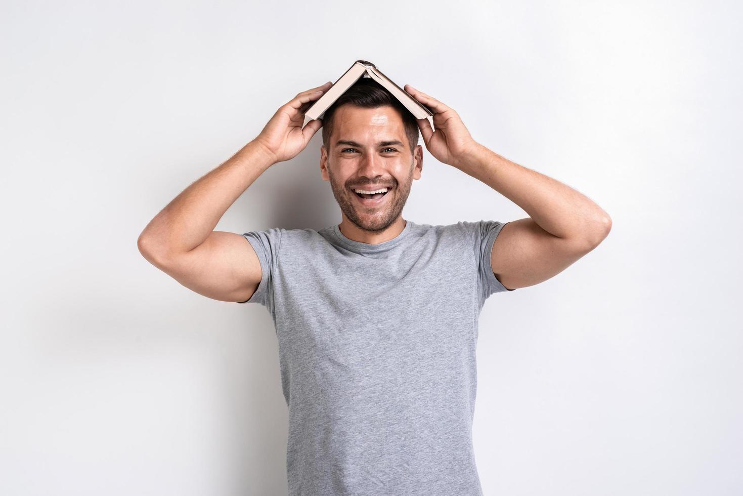 Funny man put the book on his head and happily looking at the camera.- Image photo