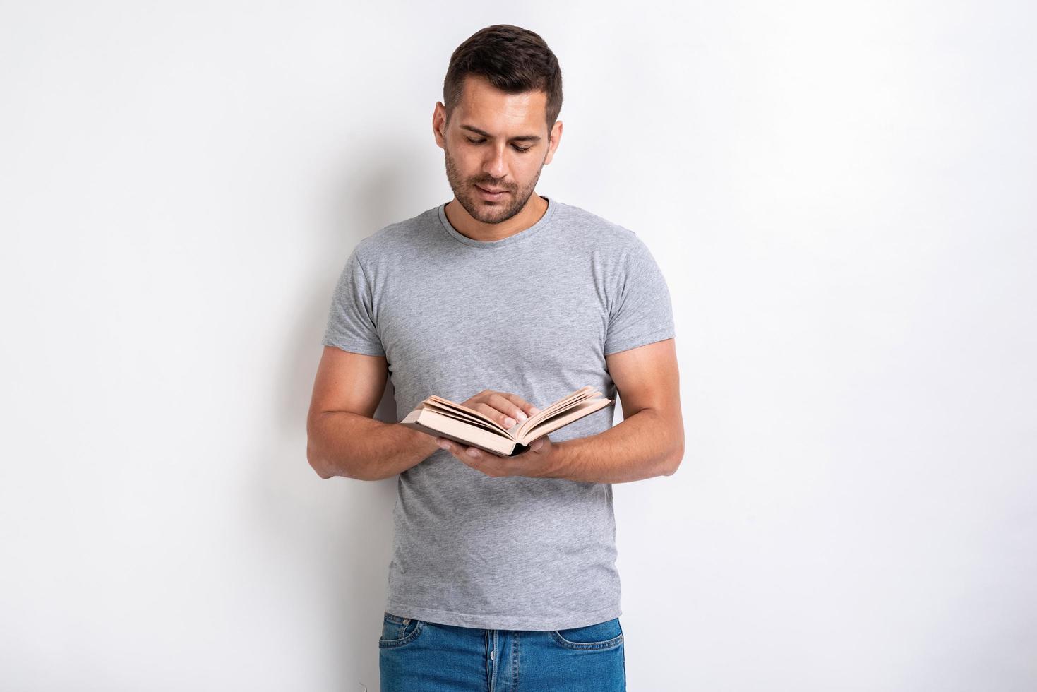 Studio shot of standing man holding a book and reading of it,- Education concept photo