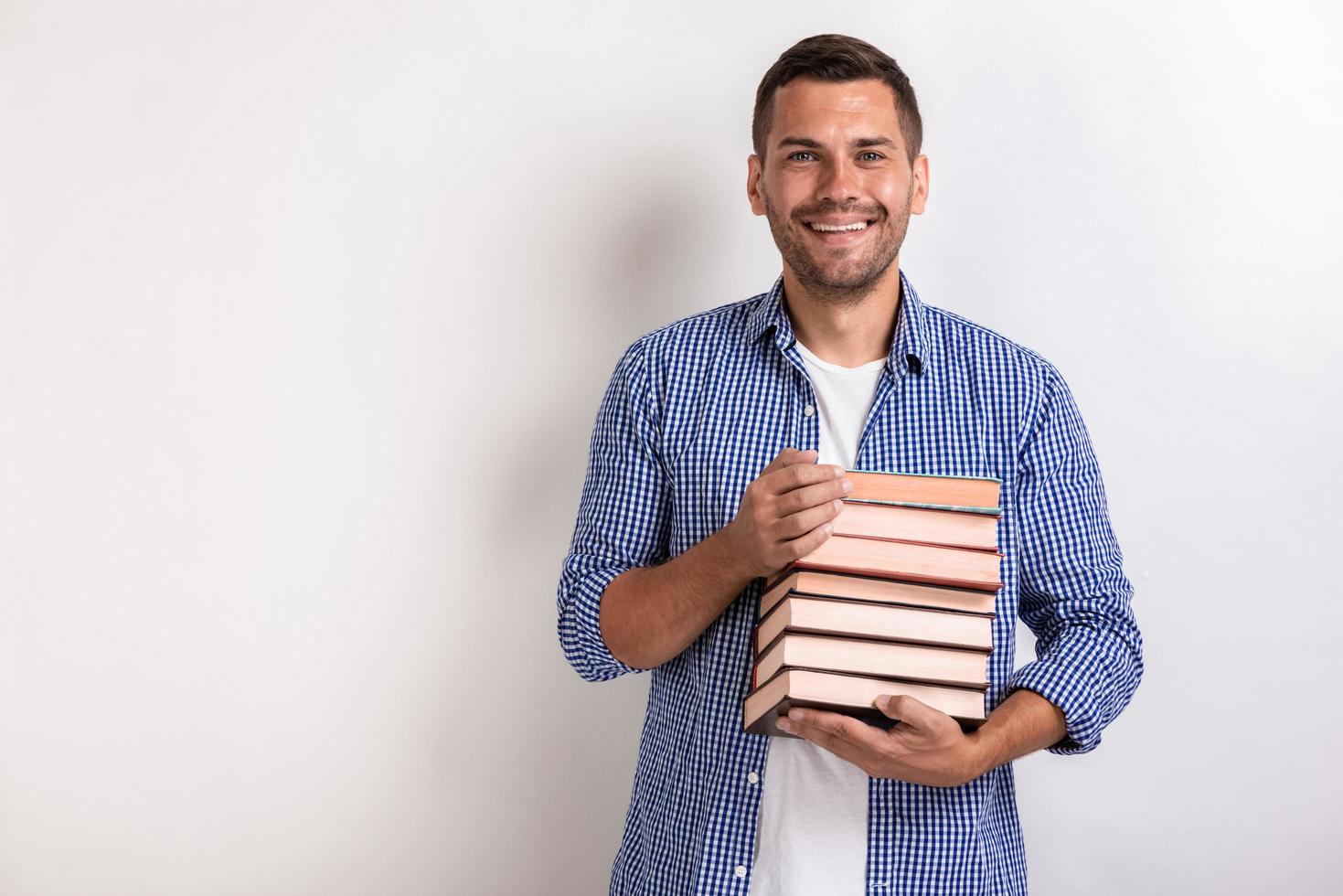 Portrait of happy nerd young man holding books in his hands. Back to school photo