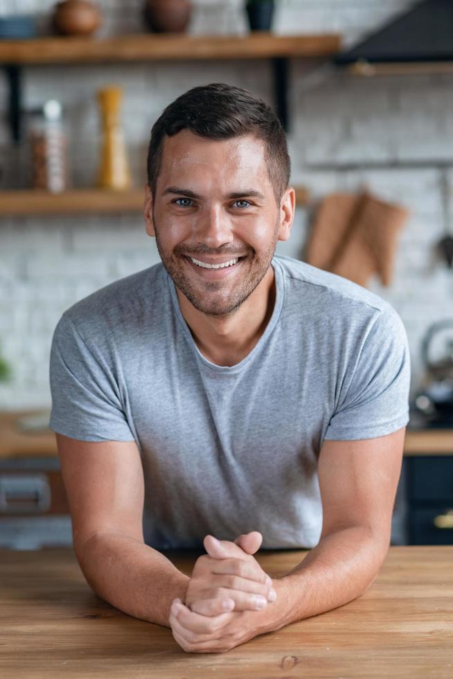 Handsome man sits at the table smiling looking at the camera.- Image photo