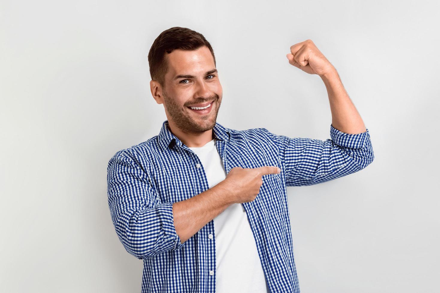 hombre feliz riendo y señalando sus bíceps por su brazo.- imagen foto