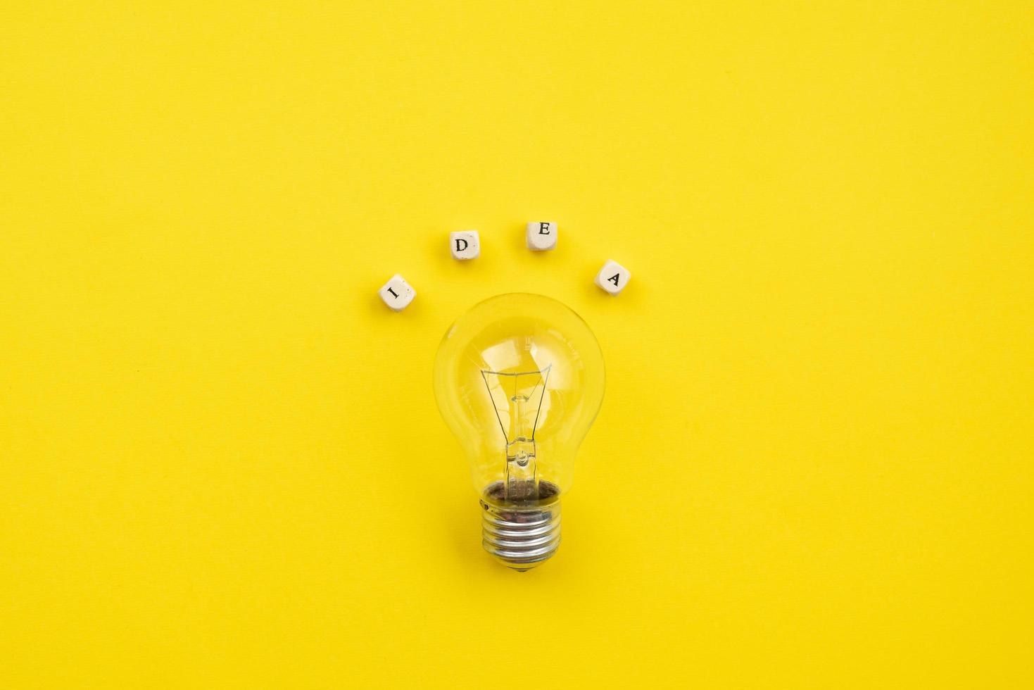 bulb on yellow background next an inscription idea - Image photo