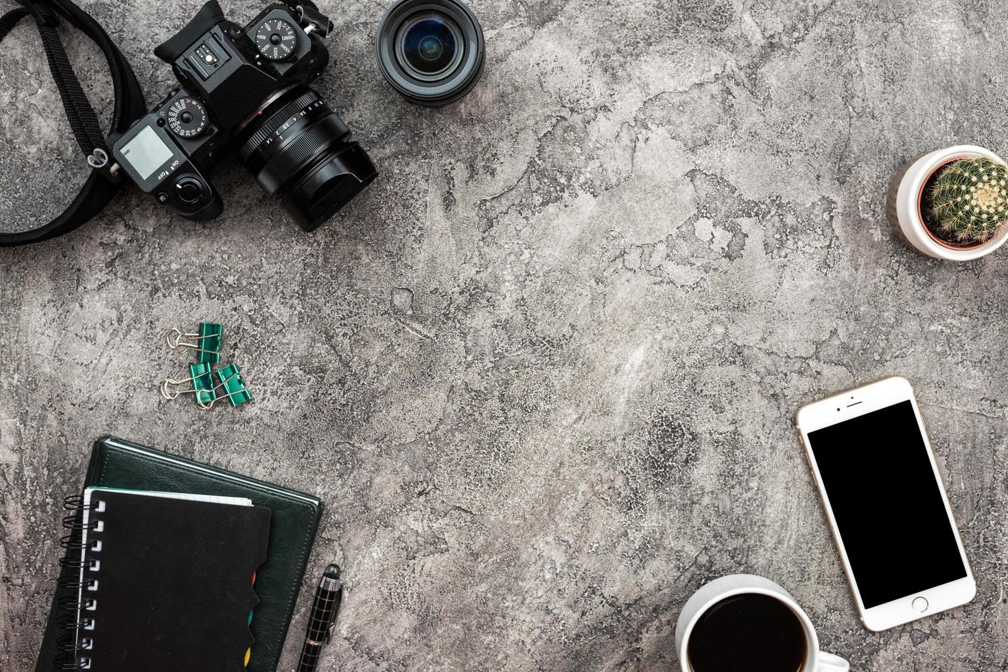 top view a plaster background with a photocamera, smartphone and stationery photo