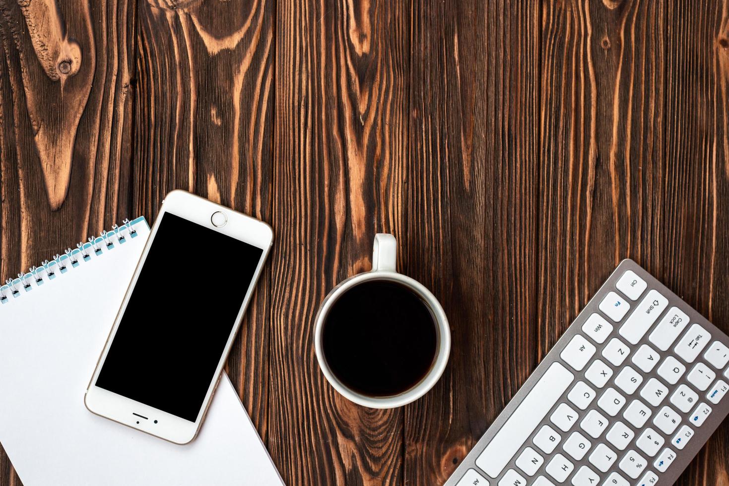 Escritorio de madera de oficina de vista superior con una taza de café y un teléfono inteligente - copyspace foto