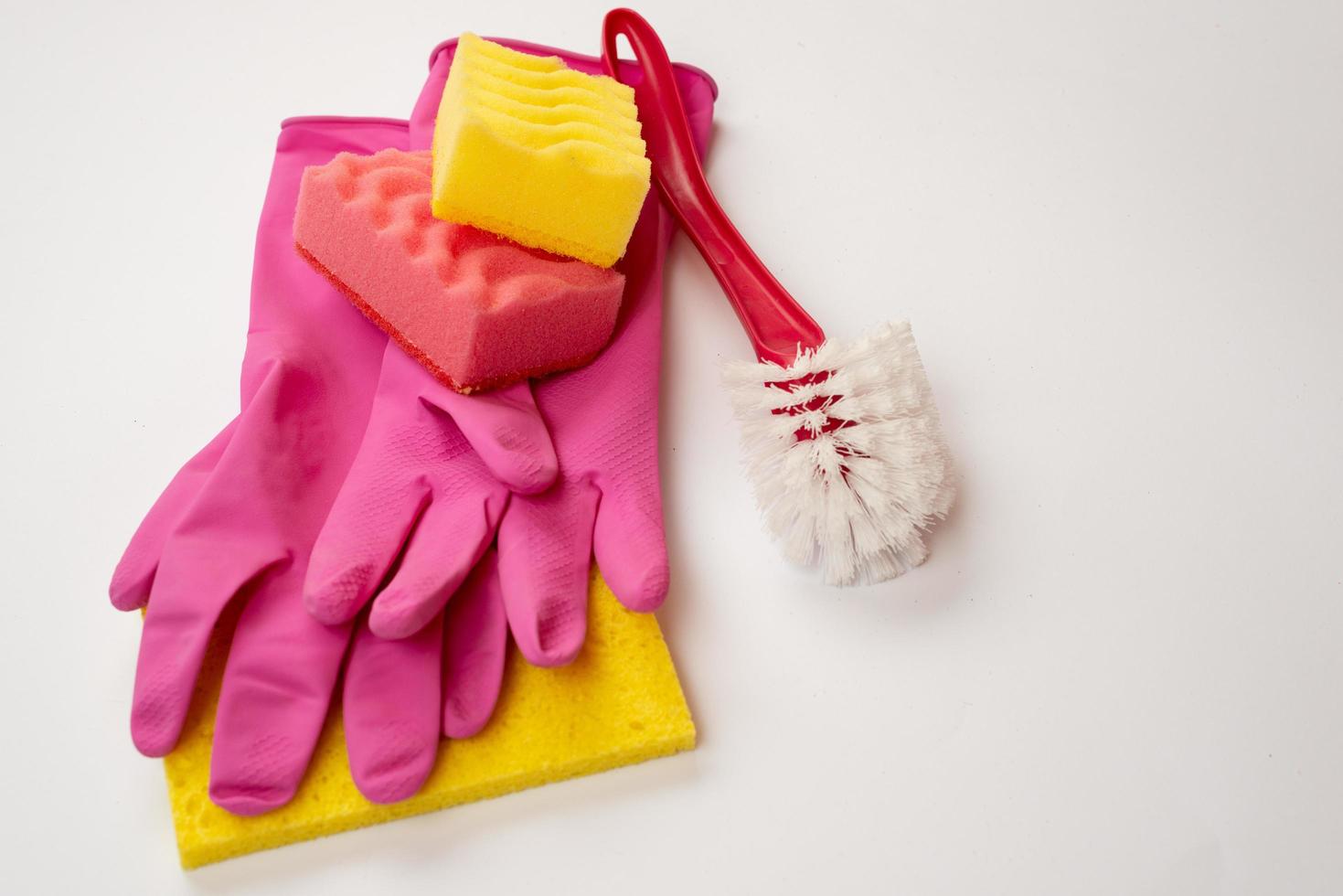 esponja, cepillo doméstico, guantes de látex sobre un fondo blanco. concepto de servicio de limpieza foto