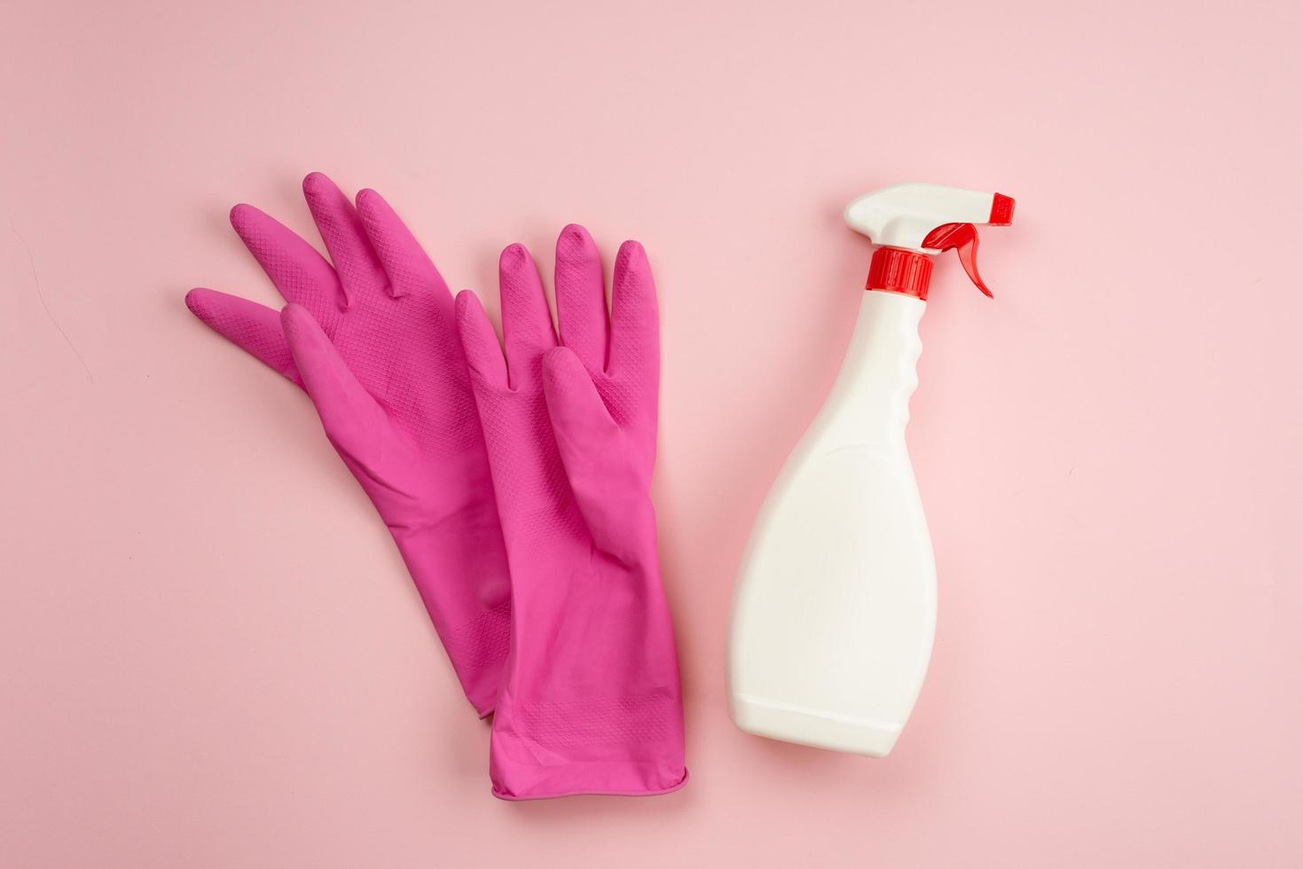 Guantes de látex, spray acostado sobre un fondo rosa, espacio de copia foto