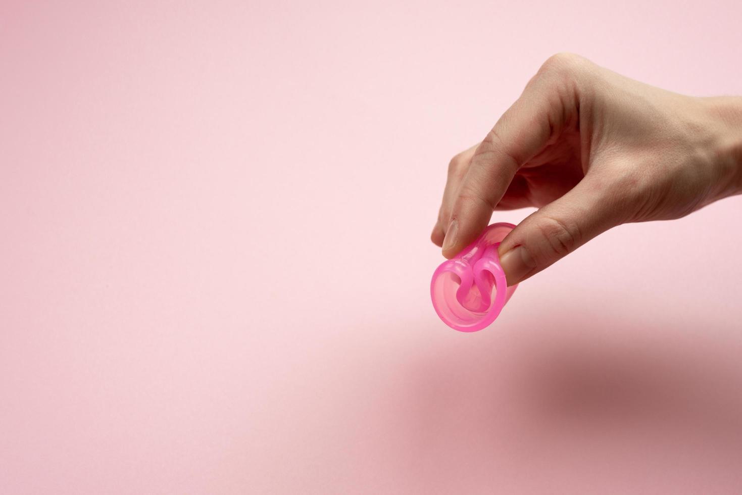 las manos femeninas muestran cómo usar una copa menstrual. foto