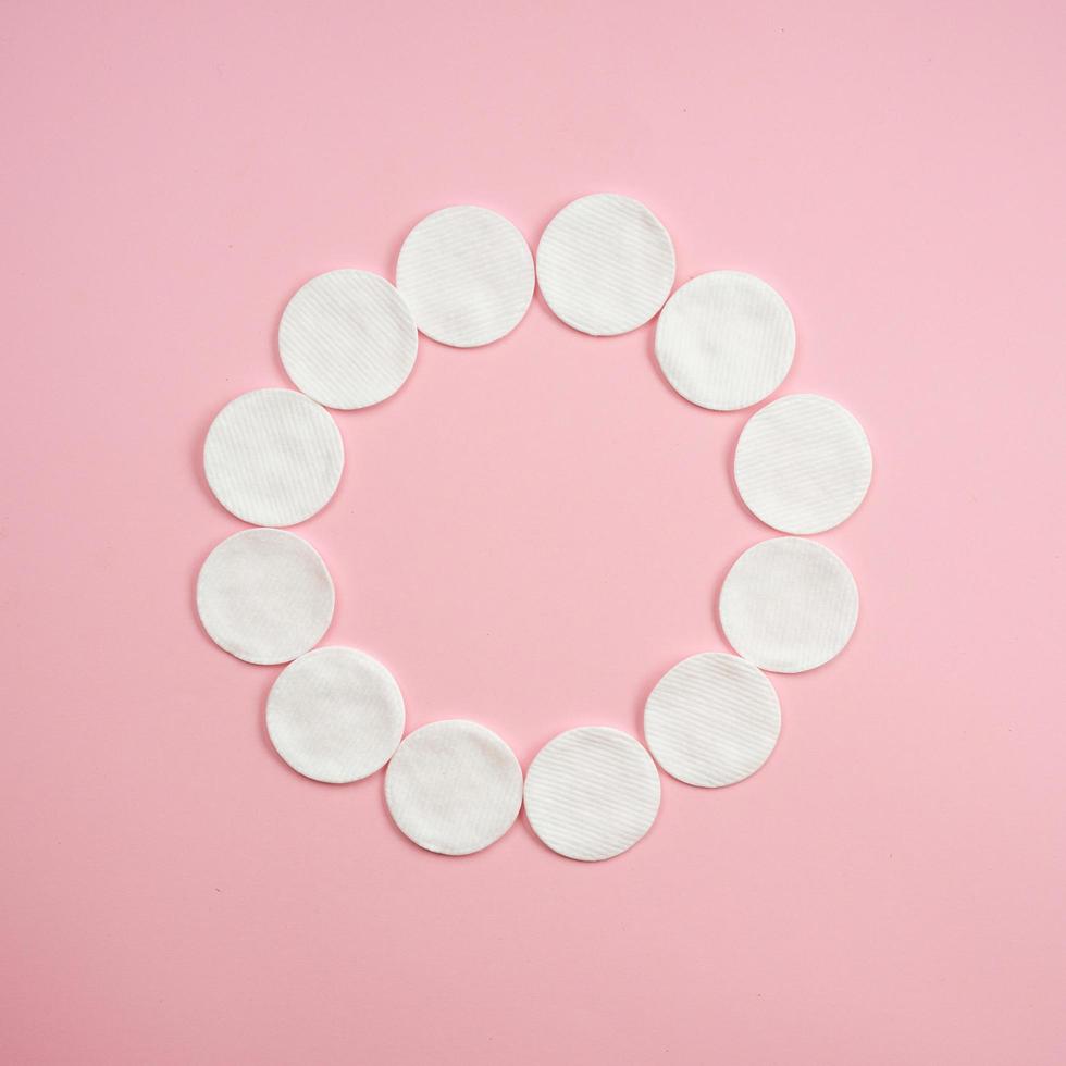 Pila de disco de algodón blanco limpio para higiene facial de belleza con enfoque selectivo sobre fondo rosa neutro. foto