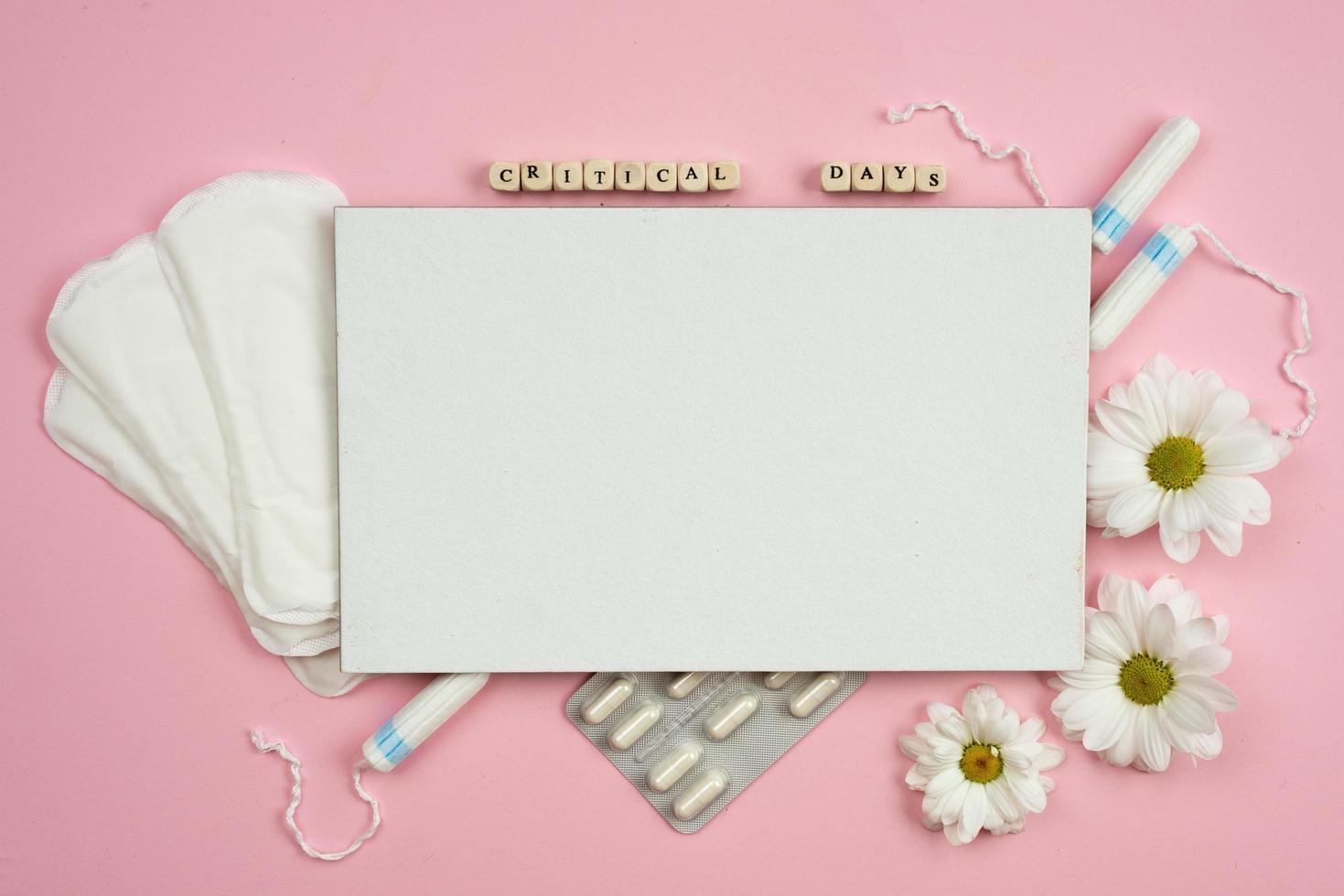 Top view of menstrual pads, tampons, and pills for period pain on the pink background.- Image photo