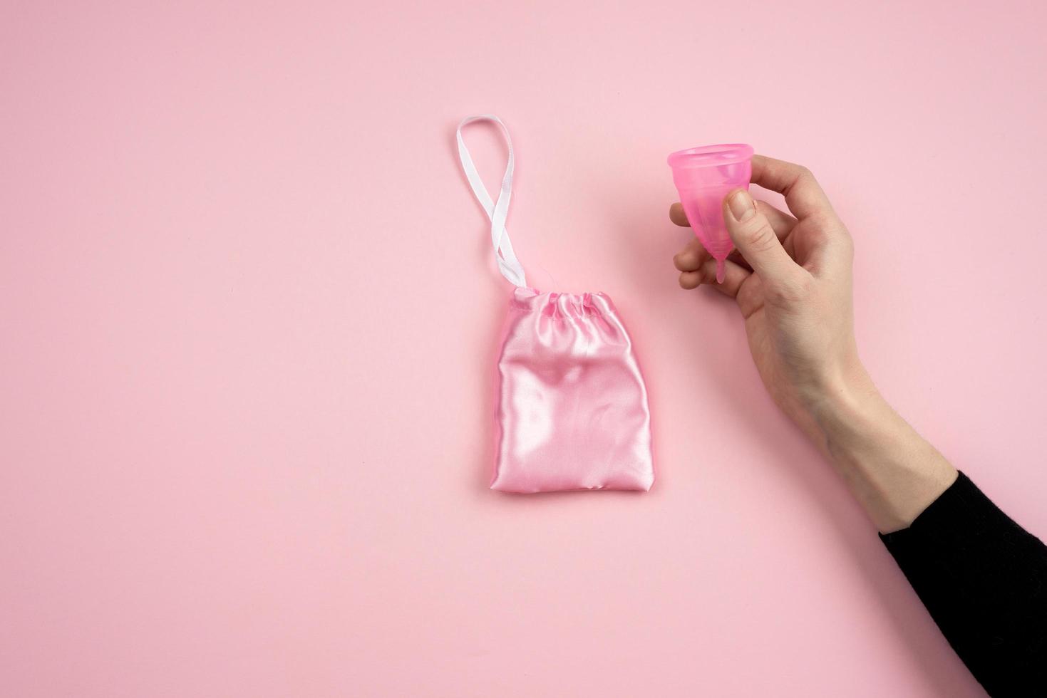 Isolated hand holding a vaginal bowl on a pink background. photo