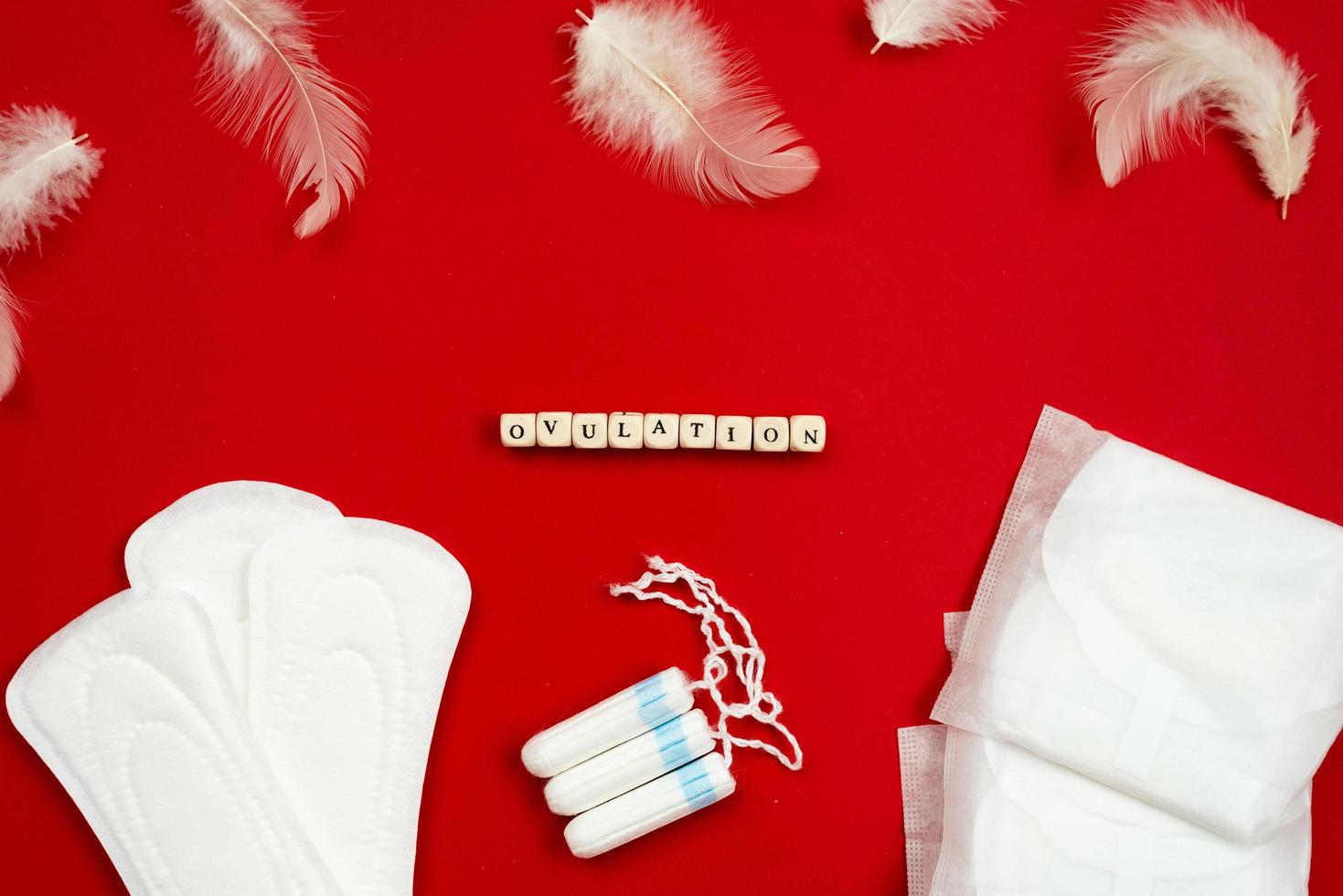 Ovulation, sanitary pads and tampons on a red background, top view. photo