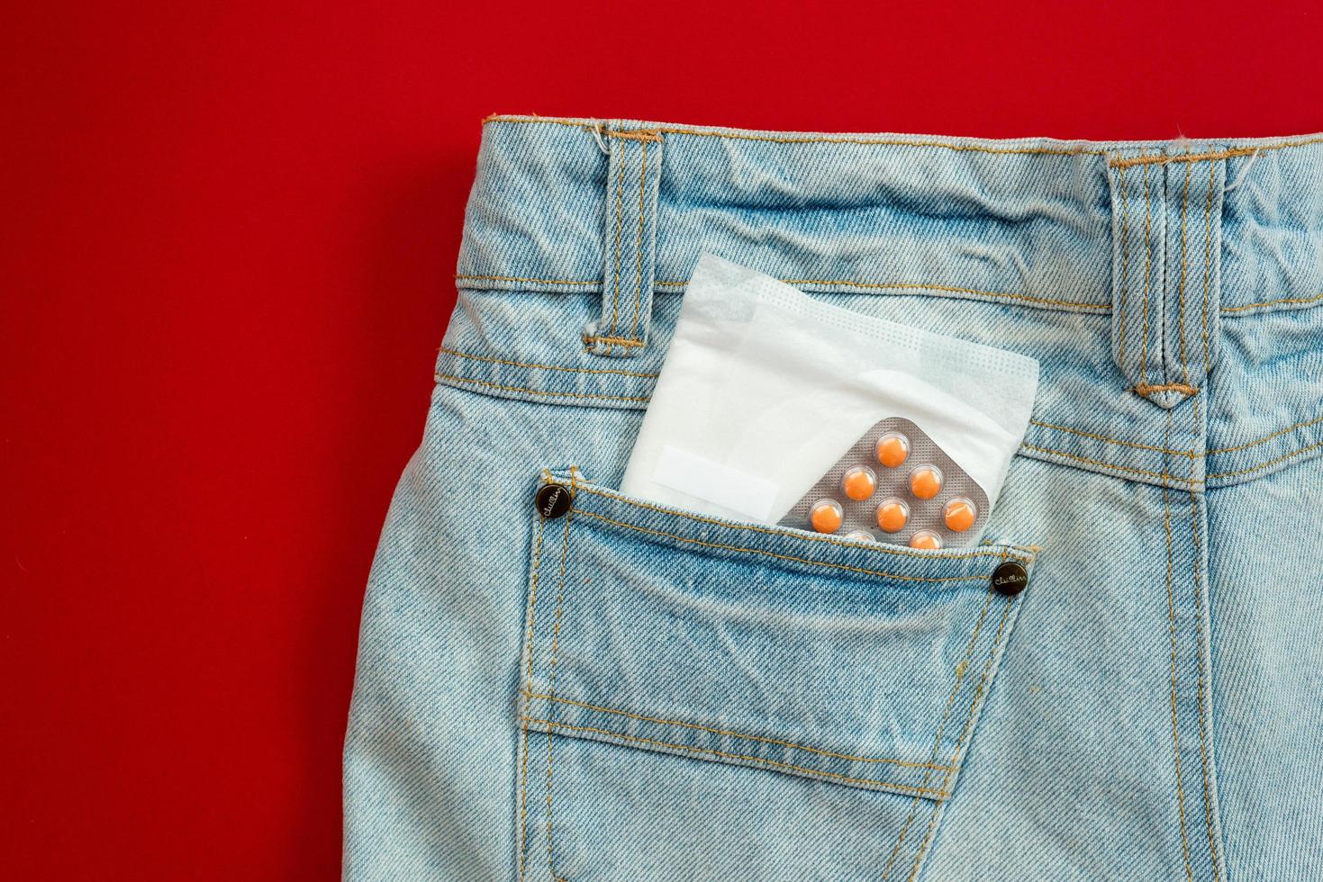Women's sanitary napkin in the pocket of jeans. photo