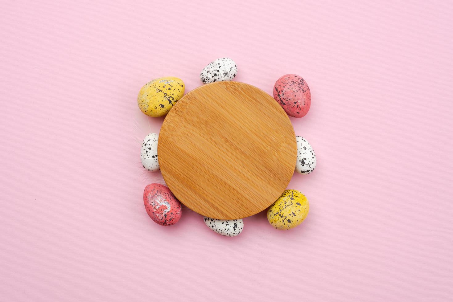 Colorful, easter eggs around wooden stand on pink background photo