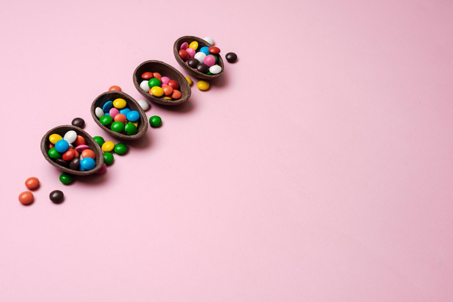 Fondo rosa pascua con caramelos multicolores en un nido de chocolate - copyspace foto