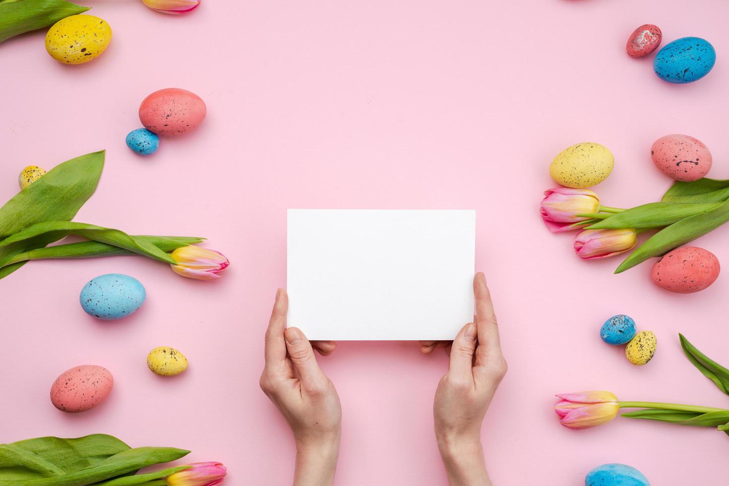 Female hands holding an empty template mockup white blank on a pink  Easter background photo