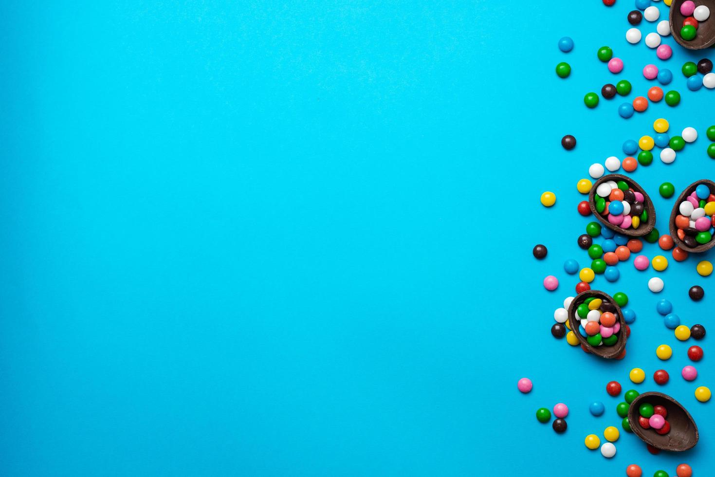 Easter blue background with multi-colored candy in a chocolate nest photo