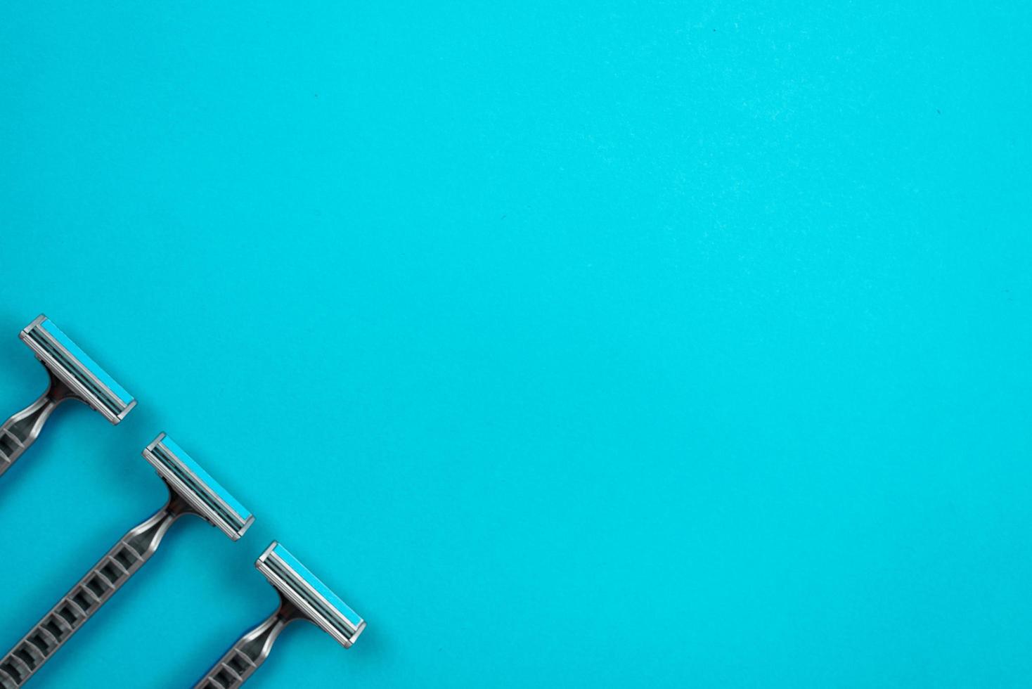 Three disposable razors are arranged diagonally on a blue background. photo